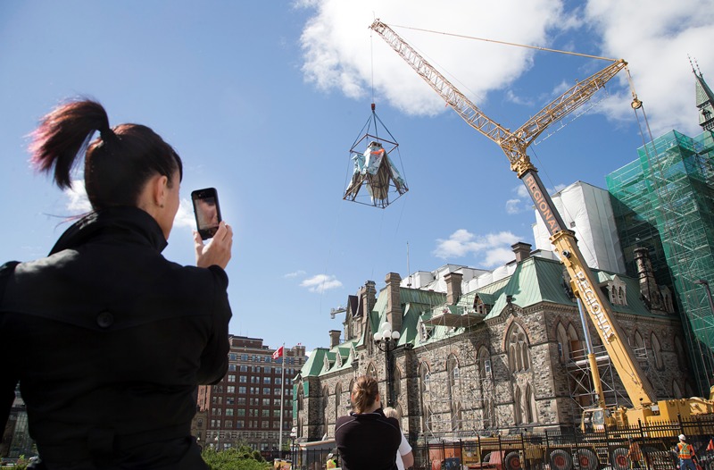 The Laurier Tower at the West Block on Parliament Hill is removed with the aid of a crane as reconstruction continues. A former staffer to a Conservative Senator has been charged with fraud and breach of trust in connection to the West Block's renovations.